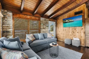 The interior living room of a vacation rental house. Cathedral ceiling, rock walls, and wooden floors.